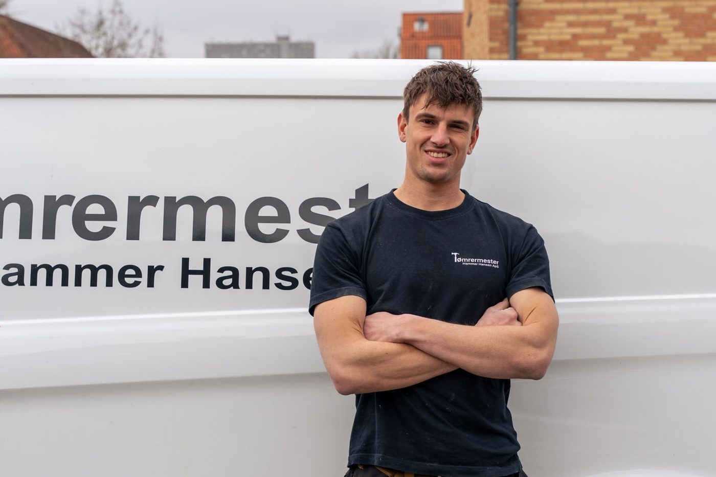 Rune, tømrermester og indehaver af Tømrermester Hammer Hansen, din tømrer i Ballerup, smiler foran firmabilen